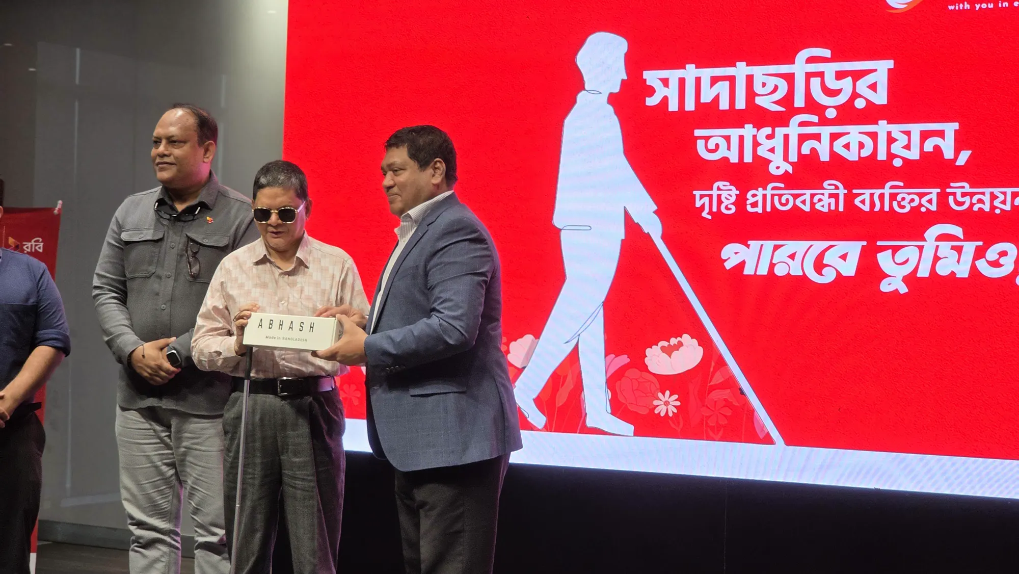 A visually impaired man with a white cane receiving his Abhash device on stage